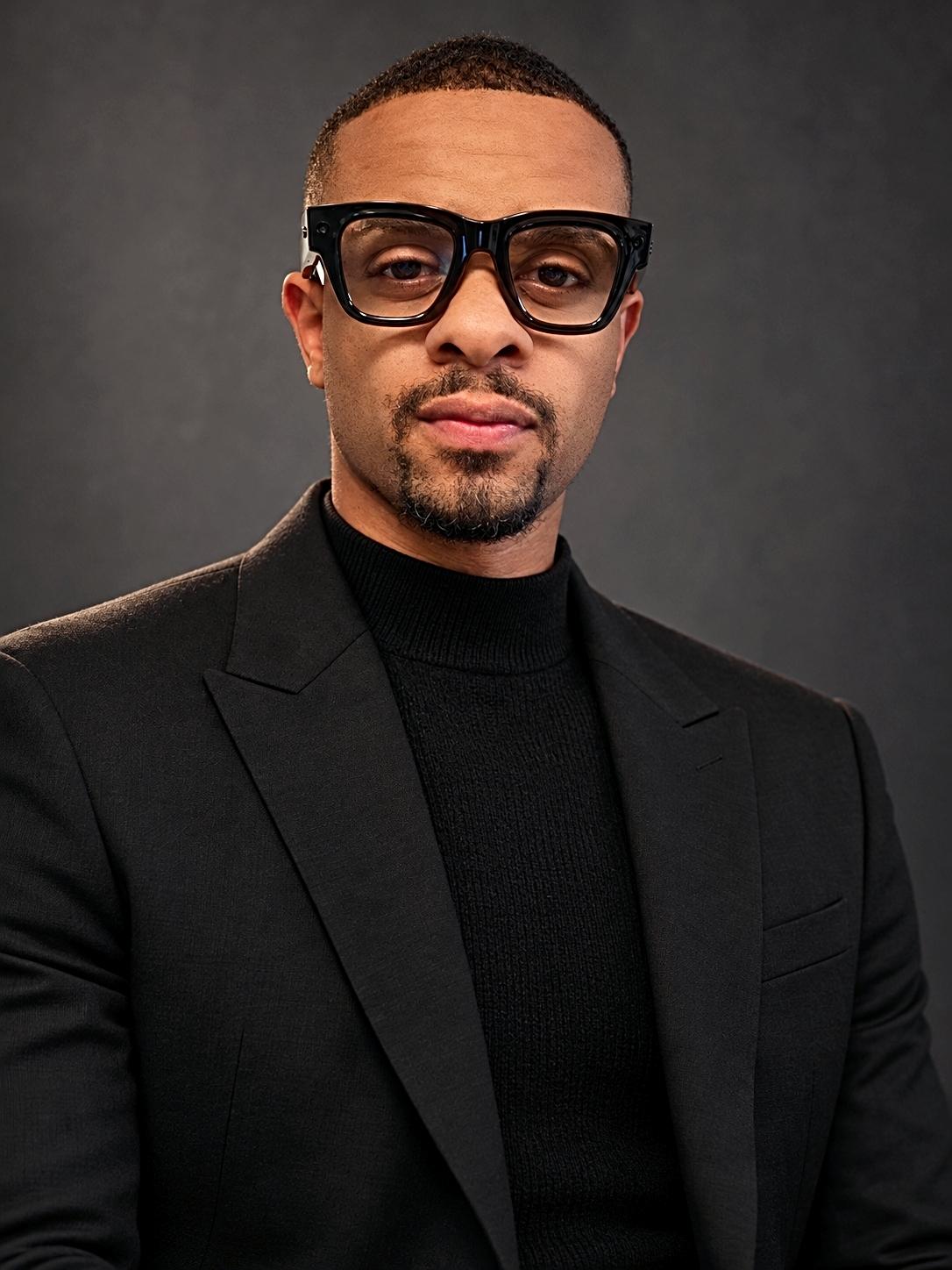 Jamaurice Holt, Founder and CEO of ArkCloud Health LLC, in a black suit and turtleneck — studio portrait
